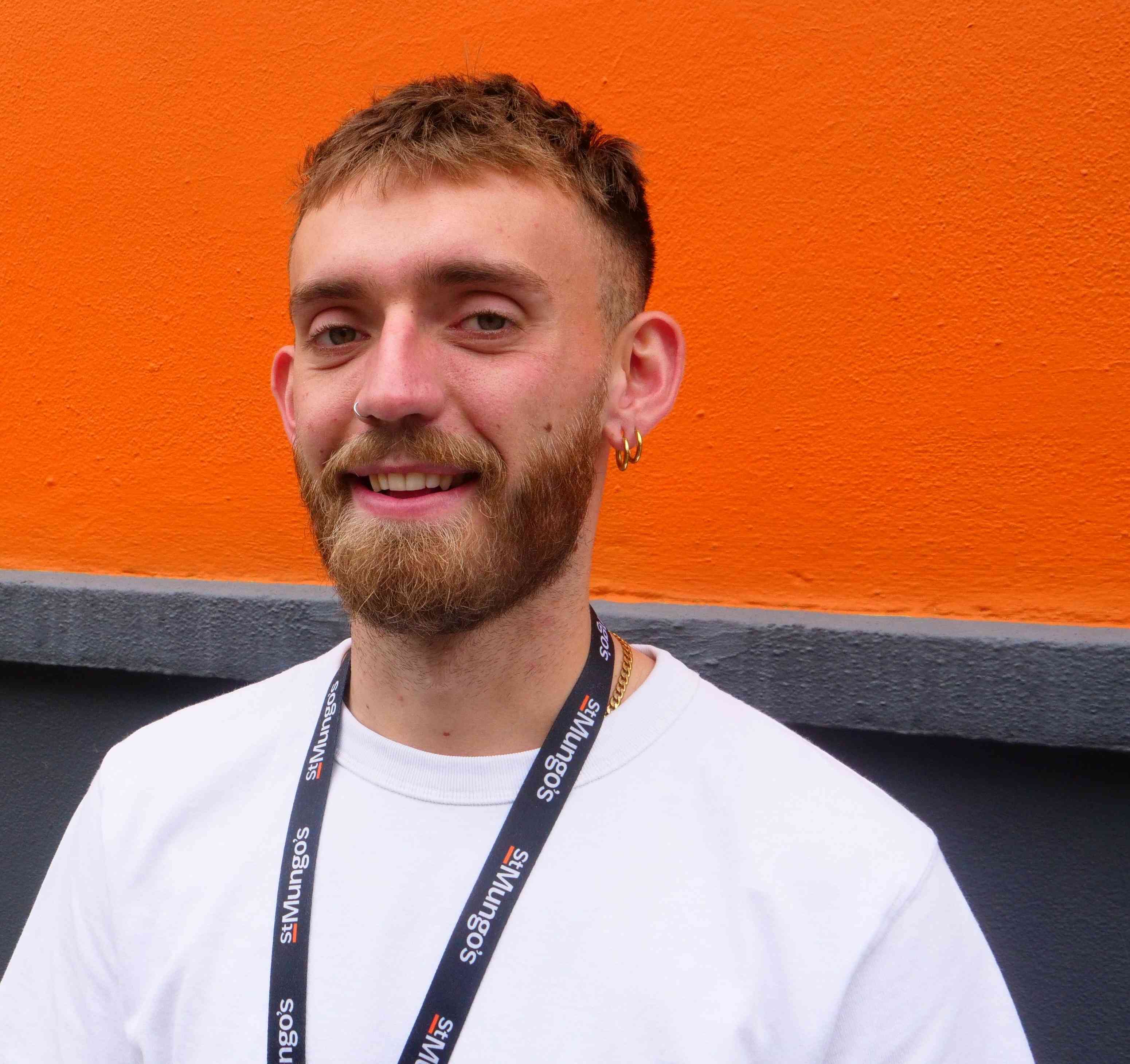 Image of a person up close and smiling into the camera, wearing a white tee shirt.